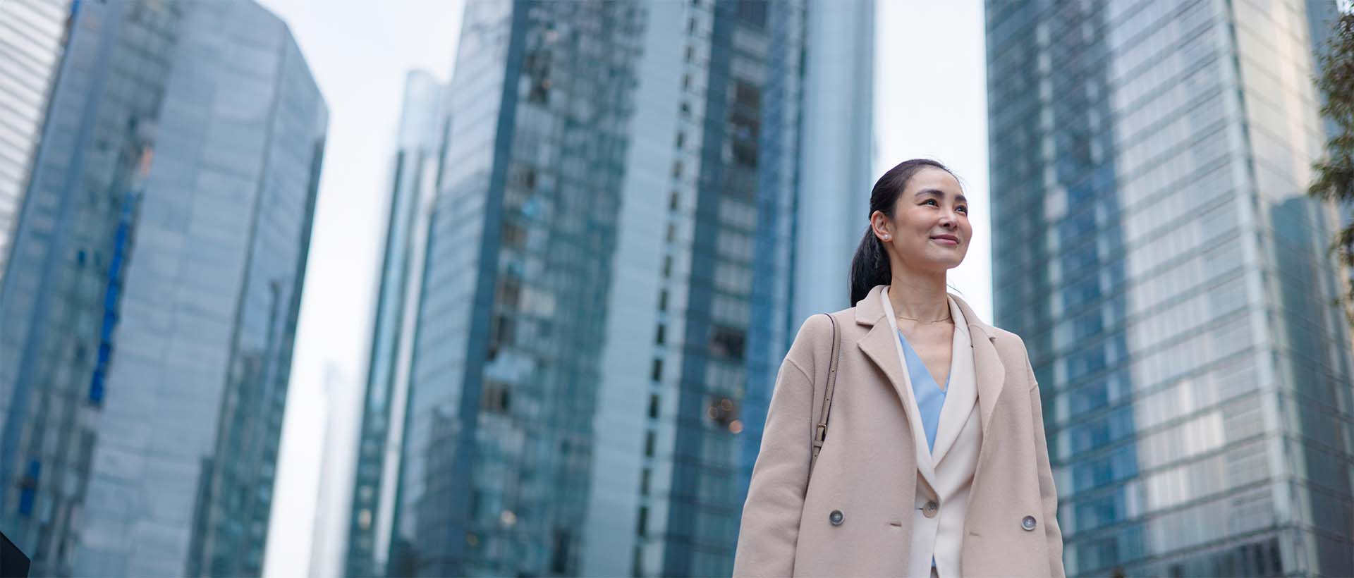 Confident businesswoman walking in a city surrounded by tall glass office buildings.